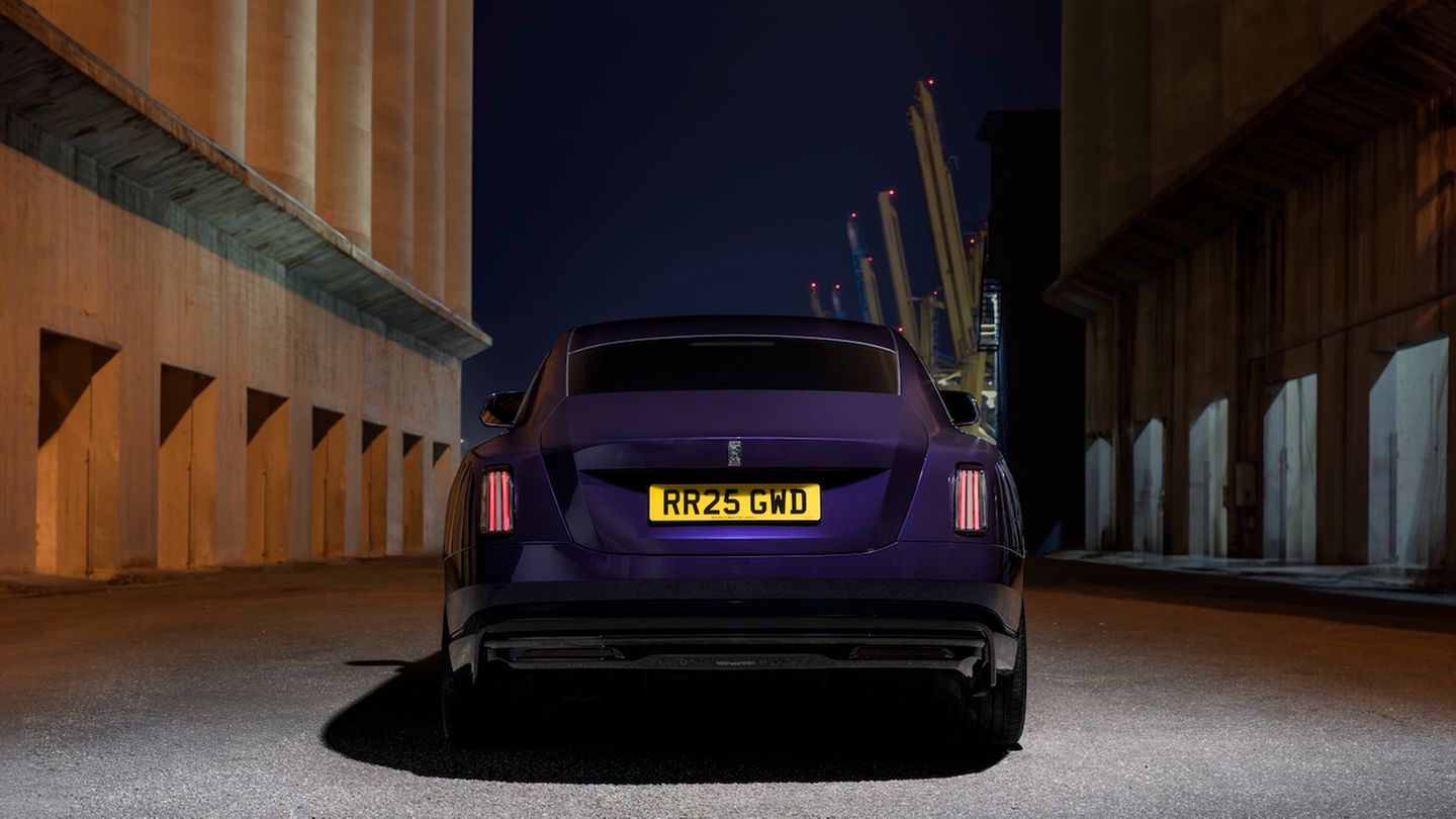 Ein lilaner Rolls-Royce beim Fahren auf der Straße von hinten fotografiert