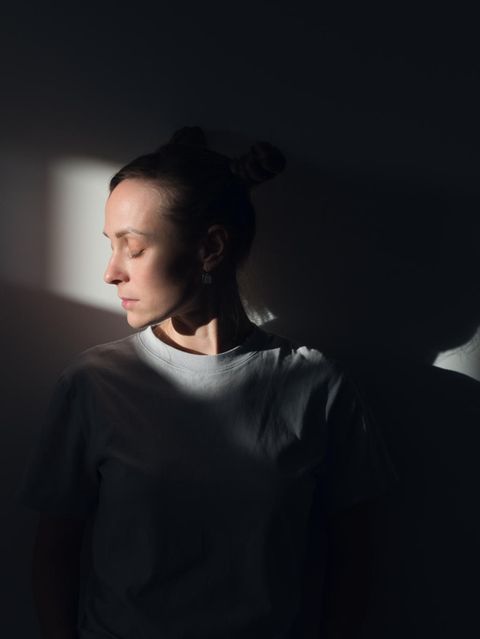 Frau steht im Lichtkegel eines dunklen Zimmers