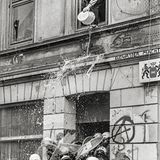 Ein Hausbesetzer schüttet einen Eimer Wasser auf Polizisten