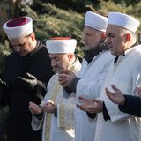 Gemeinsam mit Imamen beten während der Gedenkfeier für die Opfer des Anschlags Hinterbliebene vor einem Grabstein in Hanau