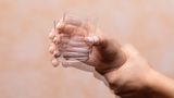Illustration eines in der Hand wackelnden Trinkglases