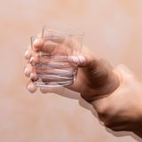 Illustration eines in der Hand wackelnden Trinkglases