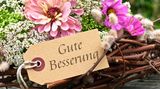 Blumen mit Schild "Gute Besserung"