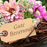 Blumen mit Schild "Gute Besserung"