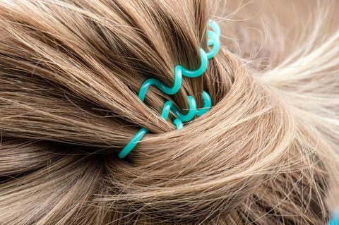 Blonde Haare, die mit einem türkisenen Zopfgummi zusammengebunden sind