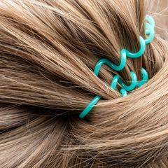 Blonde Haare, die mit einem türkisenen Zopfgummi zusammengebunden sind