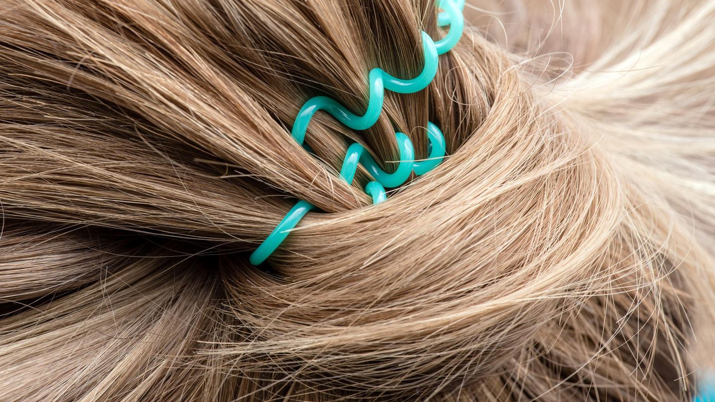 Blonde Haare, die mit einem türkisenen Zopfgummi zusammengebunden sind