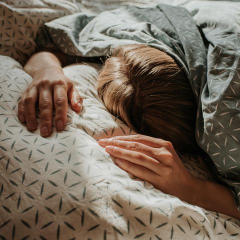 Eine Frau liegt im Bett unter ihrer Decke