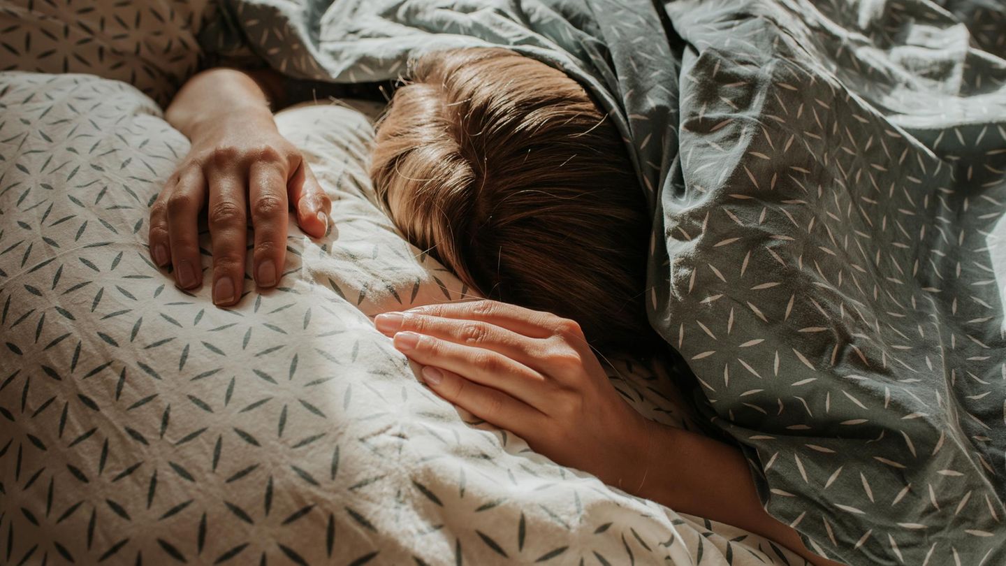 Eine Frau liegt im Bett unter ihrer Decke