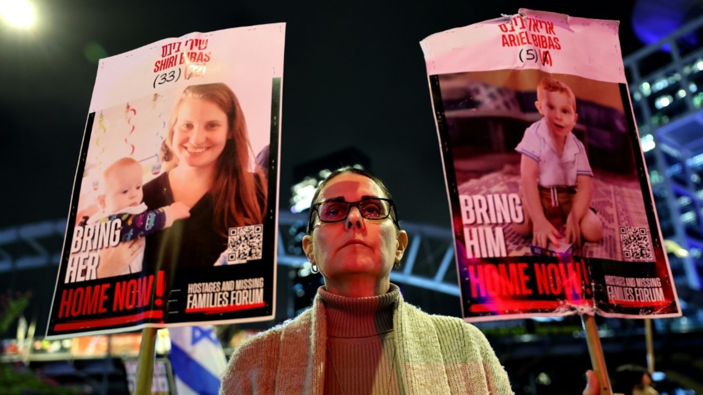 Demonstrantin in Israel mit Porträts der Bibas-Familie