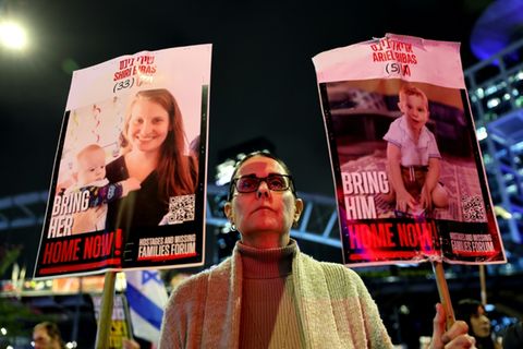 Demonstrantin in Israel mit Porträts der Bibas-Familie