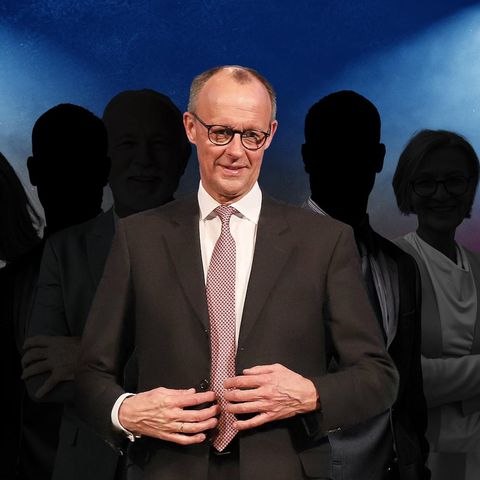 Friedrich Merz steht im Vordergrund, im Hintergrund sind Personen im Schatten zu sehen
