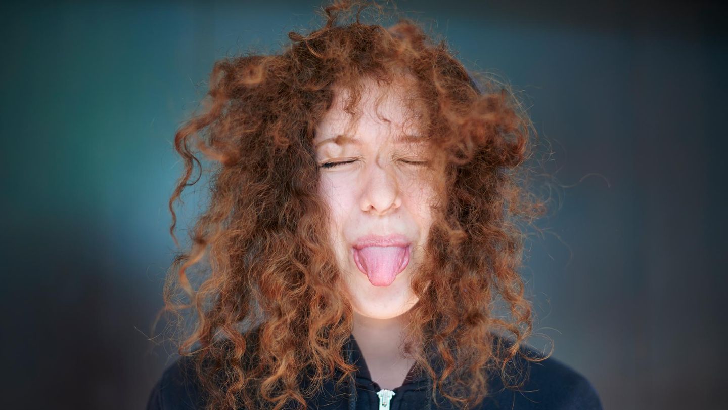 Junge Frau streckt ihre Zunge heraus Junge Frau streckt ihre Zunge heraus