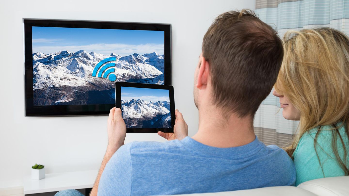 ipad auf tv spiegeln Ein Mann spiegelt den Bildschirm des iPads auf den Fernsehern
