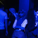 Party in Damaskus: Eine junge Frau steht gelangweilt im blauen Licht.
