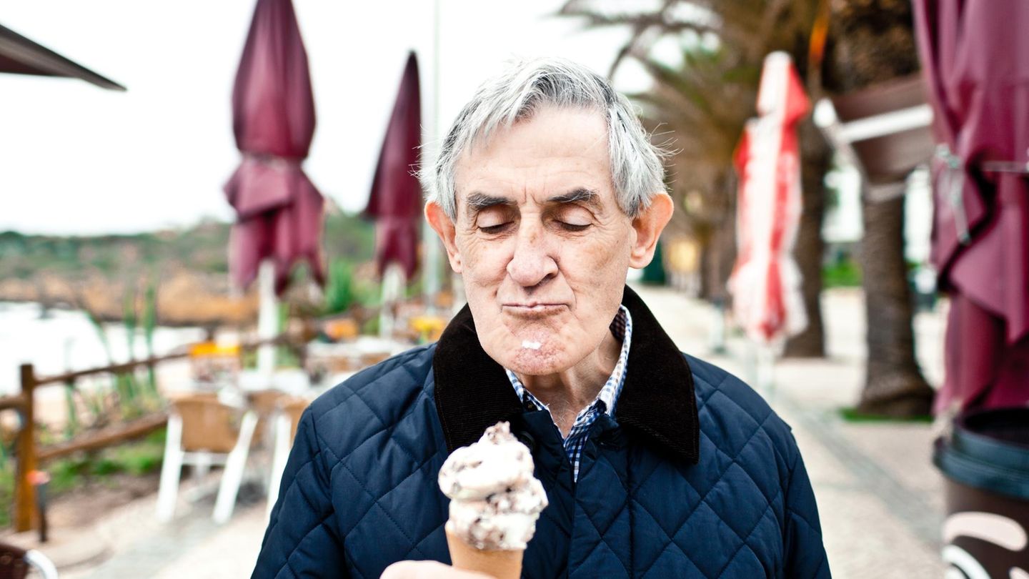 Zunge: Älterer Mann isst Eis am Strand