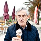 Zunge: Älterer Mann isst Eis am Strand