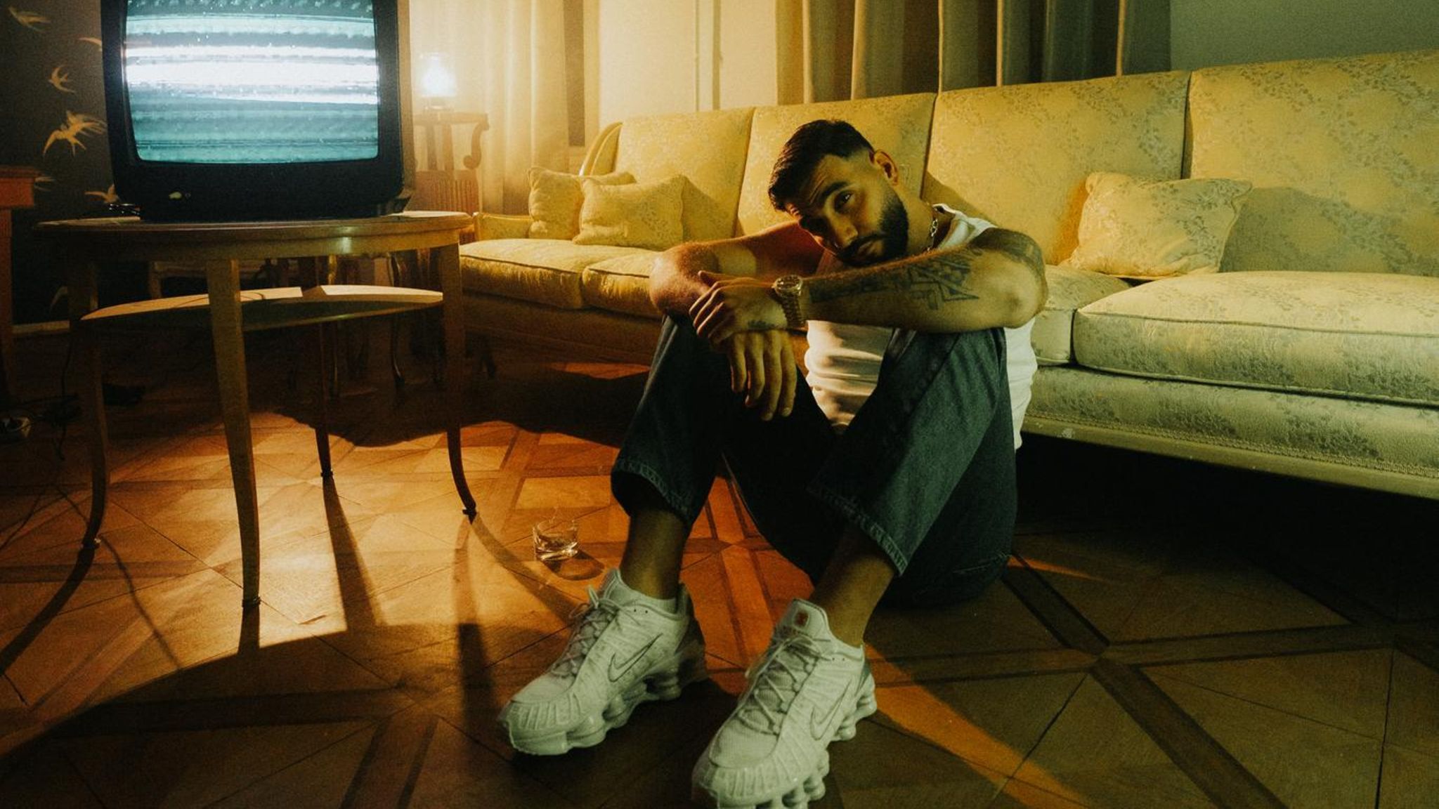 Der Rapper Samra blick in die Kamera und sitz auf dem Boden