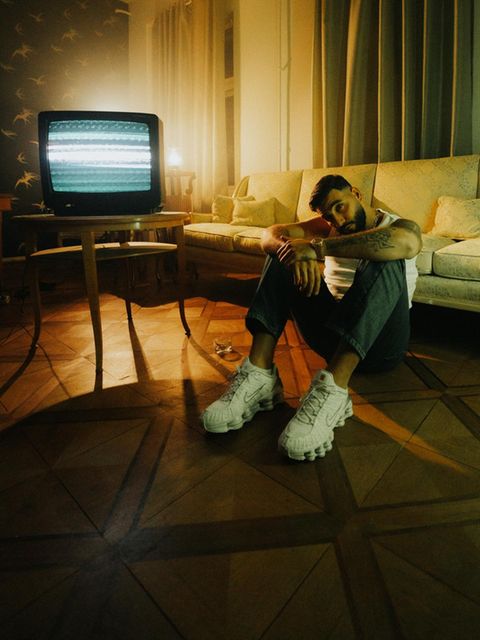 Der Rapper Samra blick in die Kamera und sitz auf dem Boden