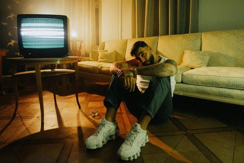 Der Rapper Samra blick in die Kamera und sitz auf dem Boden