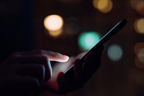 Ein Smartphone wird im Dunkeln benutzt – mit Darkmode?
