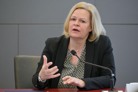 Bundesinnenministerin Nancy Faeser gestikuliert, während sie auf einem Podium in ein Mikro spricht