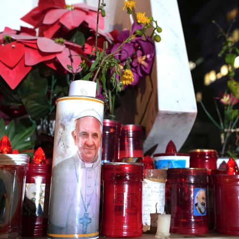 Believers pray with flowers and candles for Pope Francis