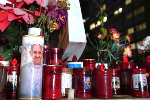 Gläubige beten mit Blumen und Kerzen für Papst Franziskus