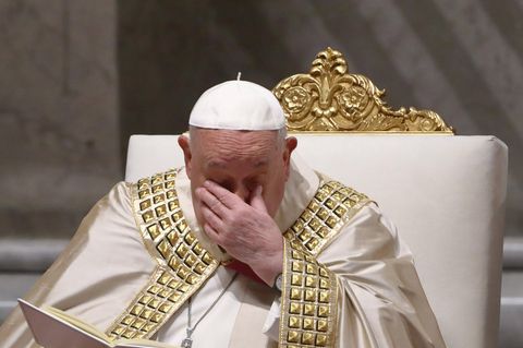 Papst Franziskus hält sich die Hand bei einer Messe vor das Gesicht