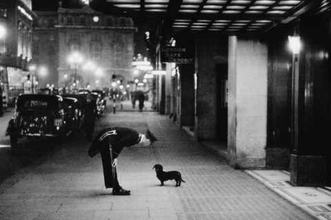 Commissionaire's Dog  A hotel commissionaire talking to a small dachshund dog in Piccadilly Circus, London. Original  Publication: Picture Post - 2 - In The Heart of the Empire - pub. 1938 