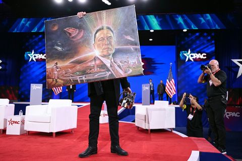 Elon Musk hält ein Bild von sich hoch