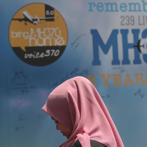 Eine junge Frau geht mit gebeugtem Kopf an einer Gedenktafel für die Verschwundenen von MH370 vorbei