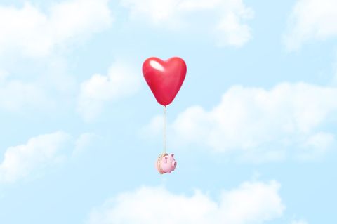 Geld in der Beziehung: Ein am Herz-Luftballon hängendes Sparschwein
