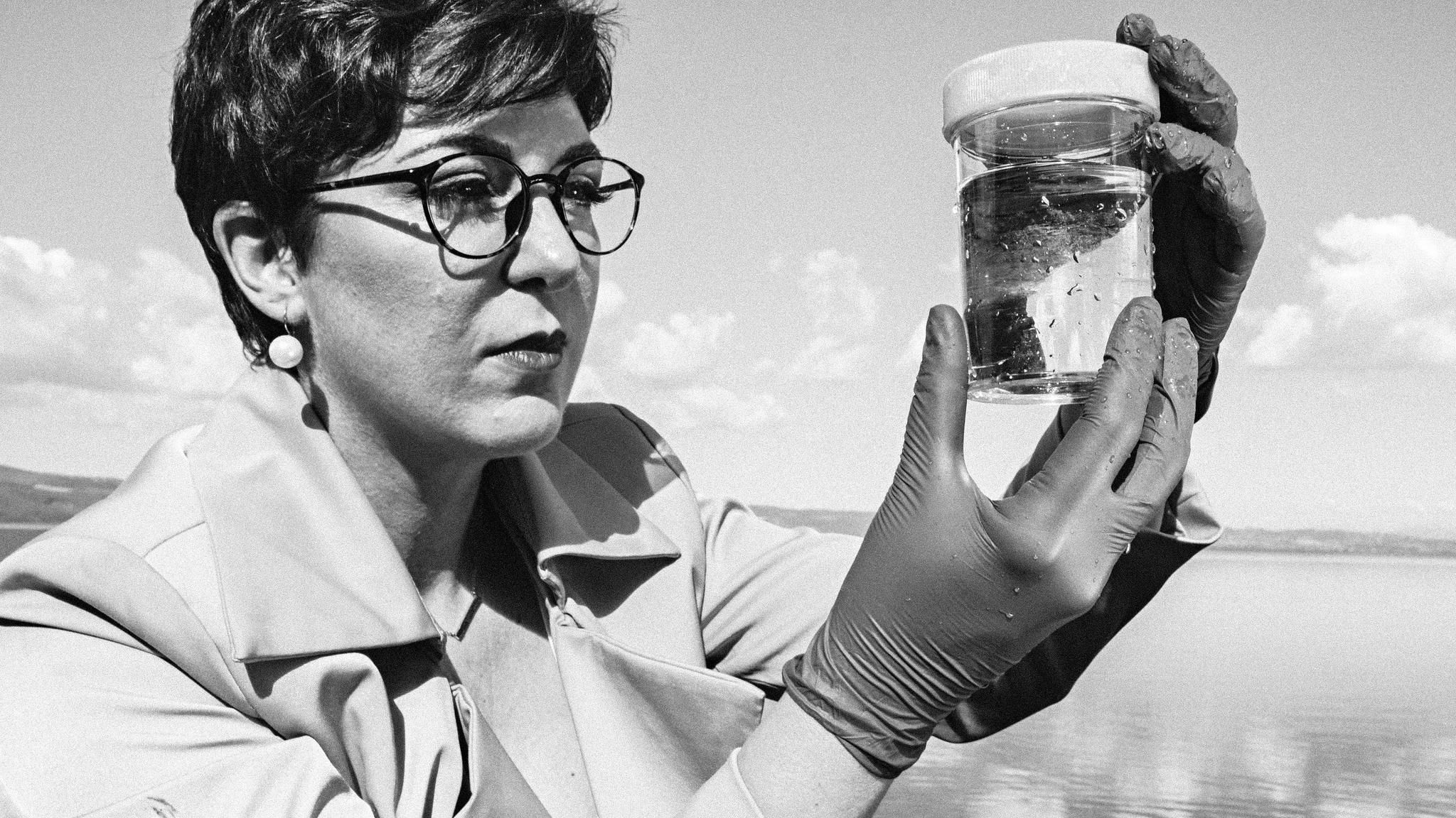 Paola Magni mit einem Glas, das eine Wasserprobe des Lago Bracciano enthält