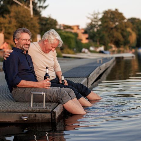 Two men drink beer on the jetty and snack over the pension with 63
