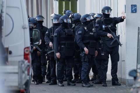 Ein schwer bewaffneter Polizei-Trupp steht am Landgericht Bielefeld auf dem Fußweg
