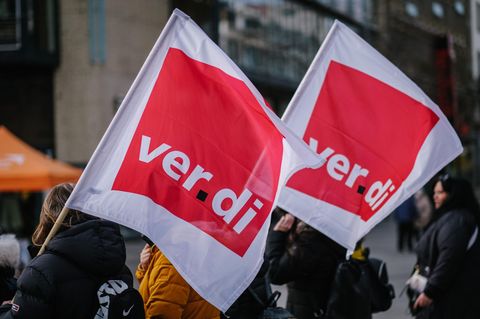 Bei einem Warnstreik tragen Angestellte Flaggen der Gewerkschaft Verdi
