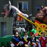 Motivwagen in Düsseldorf: Friedrich Merz zieht als Esel einen Wagen mit Säcken voller Probleme hinter sich