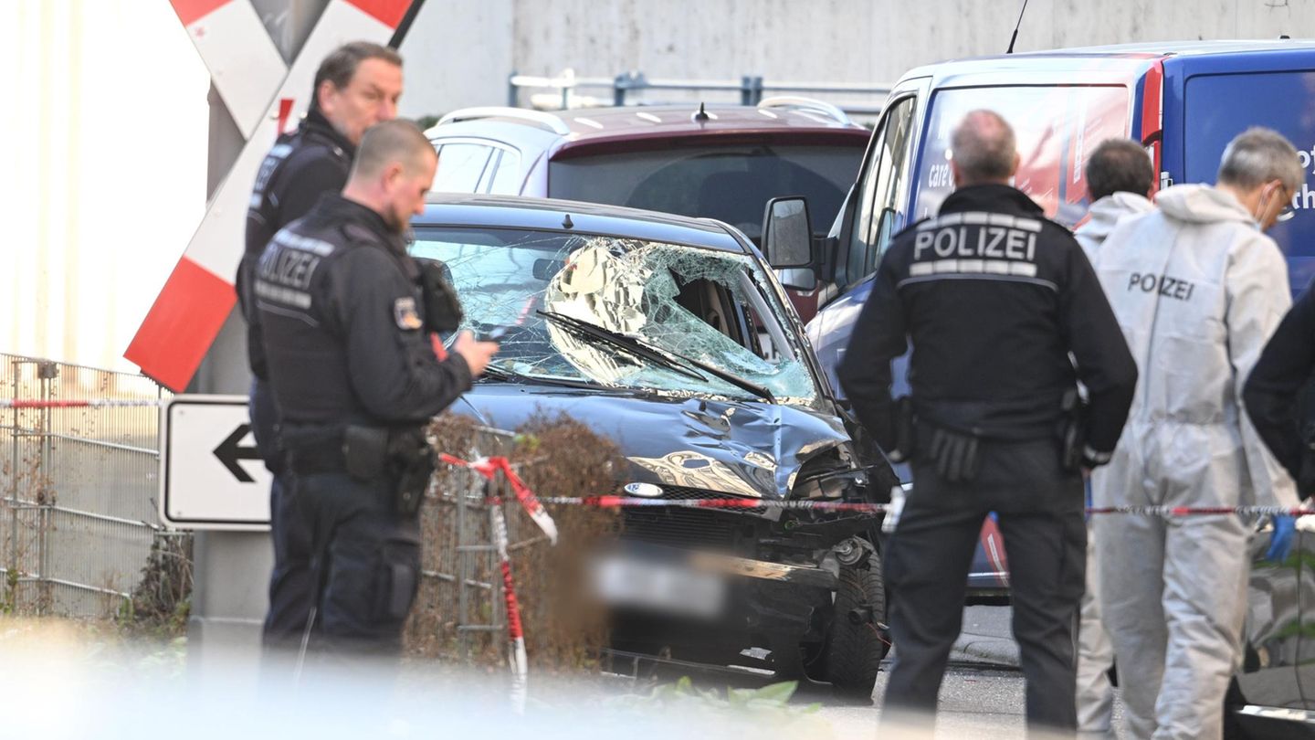 Mannheim: Einsatzkräfte der Polizei stehen bei einem Großeinsatz neben dem beschädigten Fahrzeug in der Innenstadt