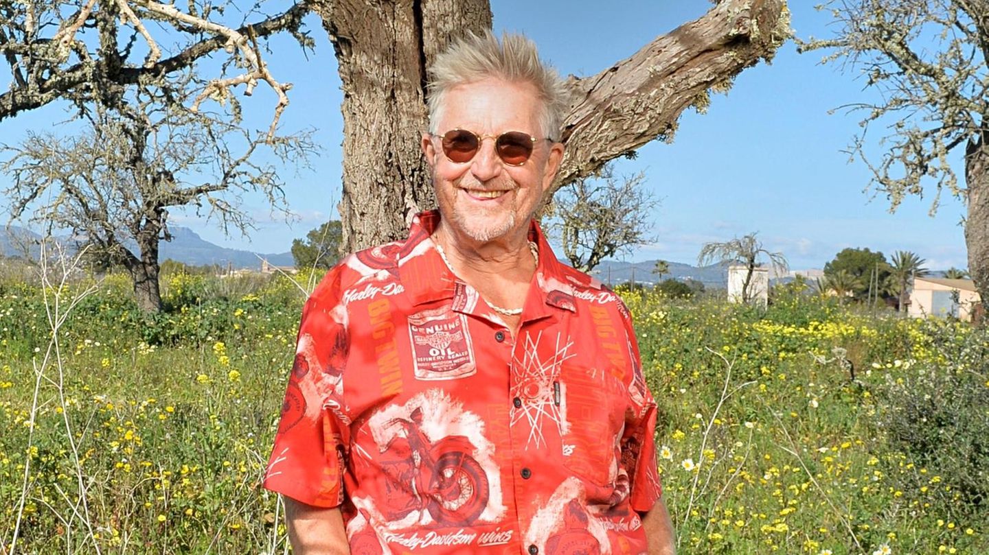 Martin Semmelrogge im roten Hemd auf seiner Finca, im Hintergrund blauer Himmel