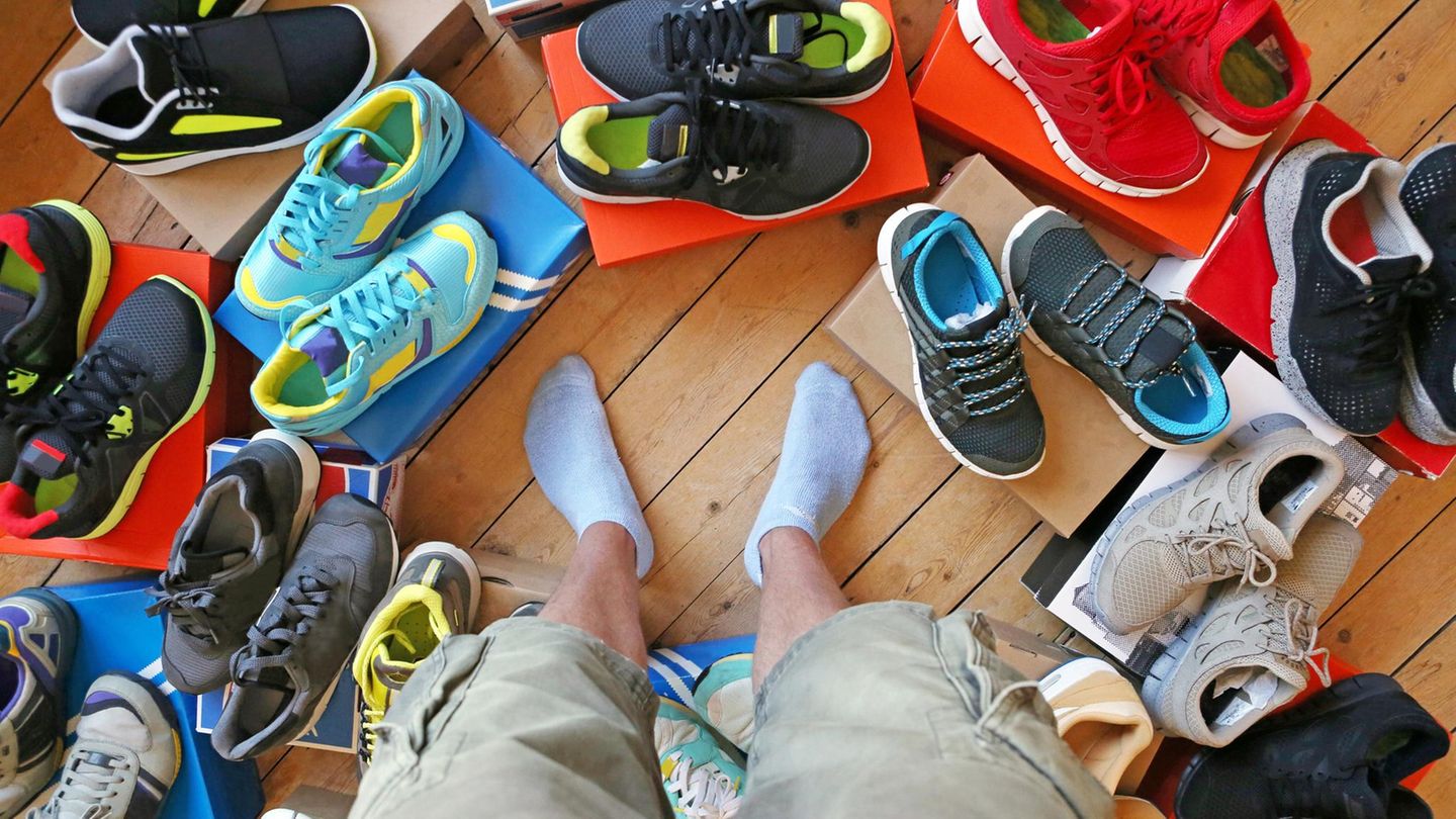 Ein Mann steht zwischen vielen Paar Schuhen