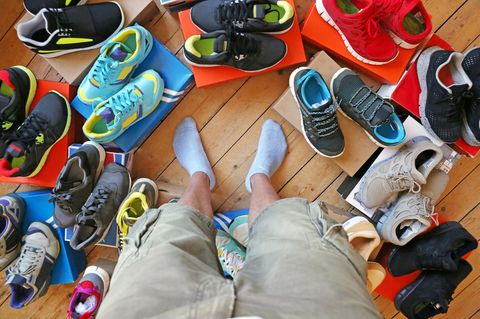 Ein Mann steht zwischen vielen Paar Schuhen