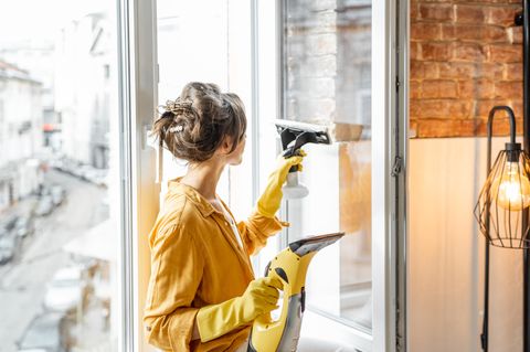 Frau putzt Fenster