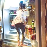 Keime: Mädchen schaut in den Kühlschrank