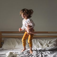 Keime: Kleinkind springt auf dem Bett