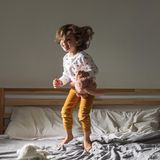 Keime: Kleinkind springt auf dem Bett