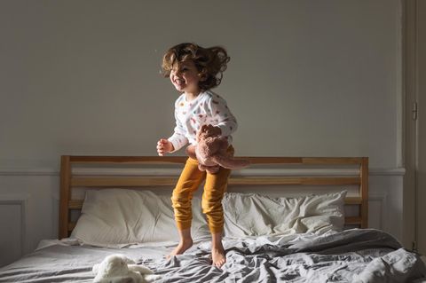 Keime: Kleinkind springt auf dem Bett