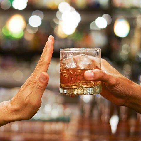 Eine Hand macht eine abwehrende Bewegung zu einem angebotenen Glas Alkohol – Fastenzeit