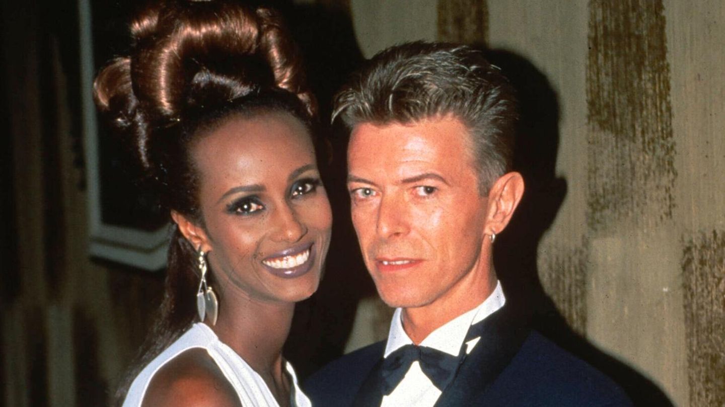 David Bowie und Ehefrau Iman, die ihre Haare zu einem riesigen Dutt hochgesteckt hat