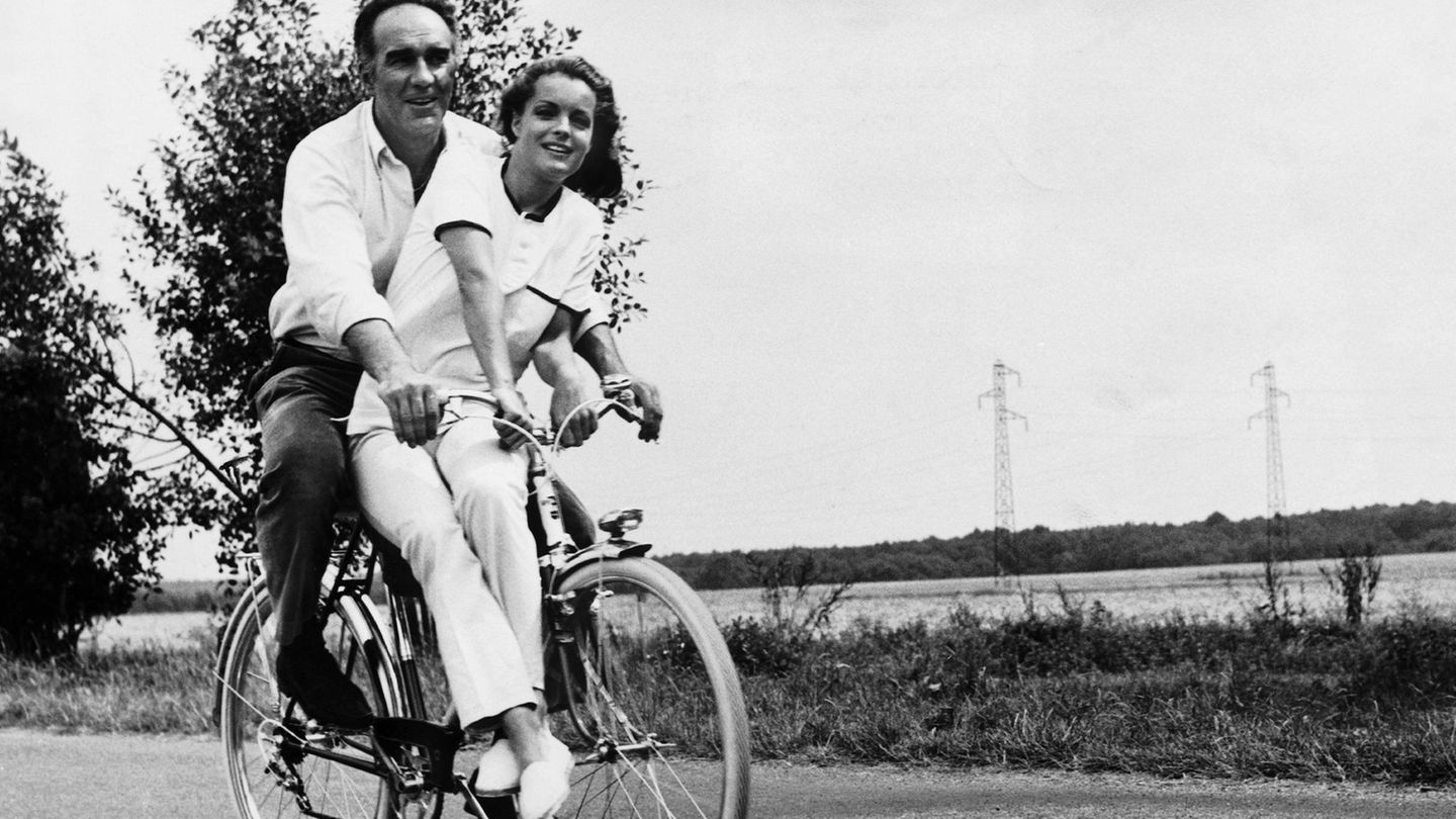 Romy Schneider sitzt mit Michel Piccoli auf dem Fahrrad, im Hintergrund Landschaft